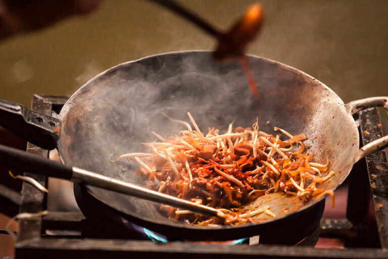 Thai chef observing food carefully during stir-frying